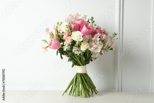 Beautiful bouquet of fresh flowers on table near white wall