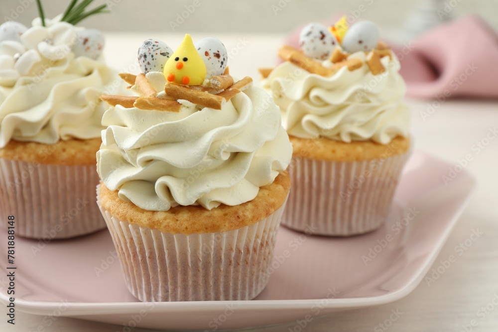 Tasty Easter cupcakes with vanilla cream on light table, closeup