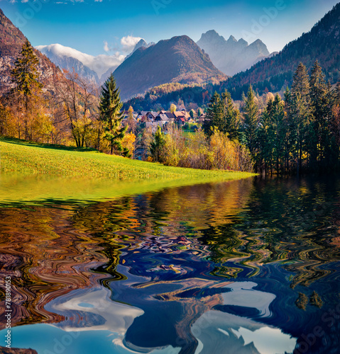 Huge peaks and green pasture reflected in the calm waters of smal lake in outskirts of Gozd Martuljek village. Stunning autumn view of Triglav mountain range in Julian Alps, Slovenia, Europe. photo