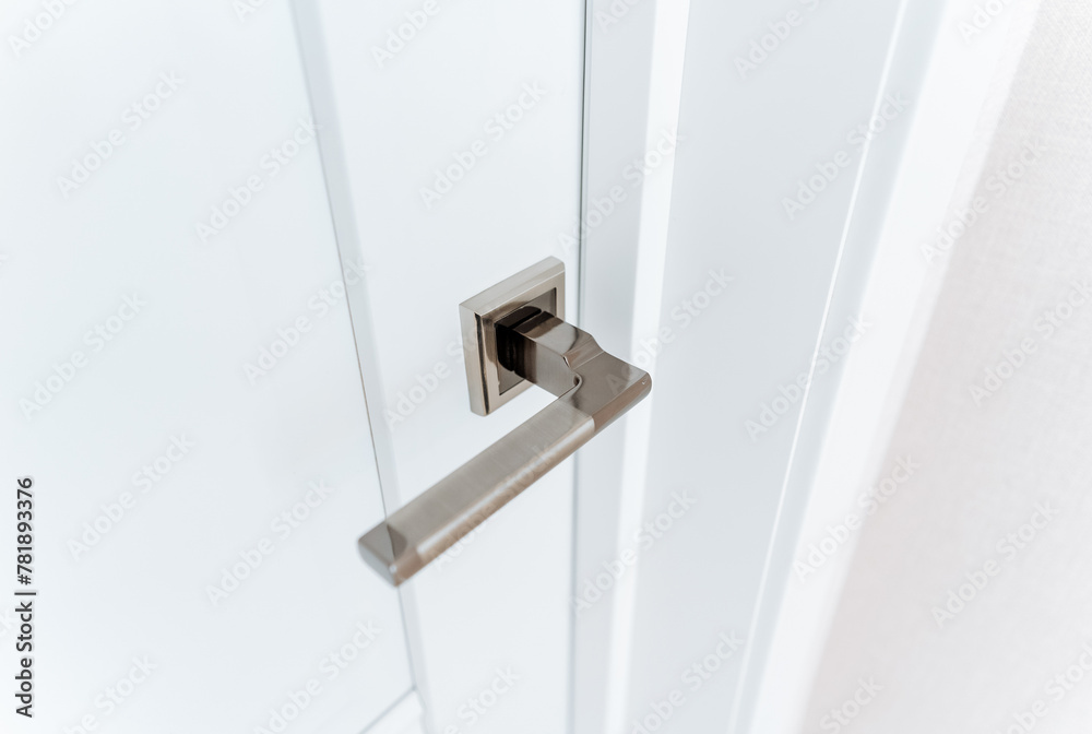 Metal door handle, closed door to room, close-up of door handle covered in chrome.