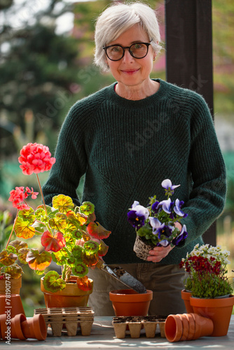 Attractive senior woman planting flowers in the garden