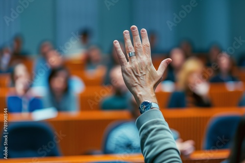 participant raising hand for a question in a crowded lecture hall