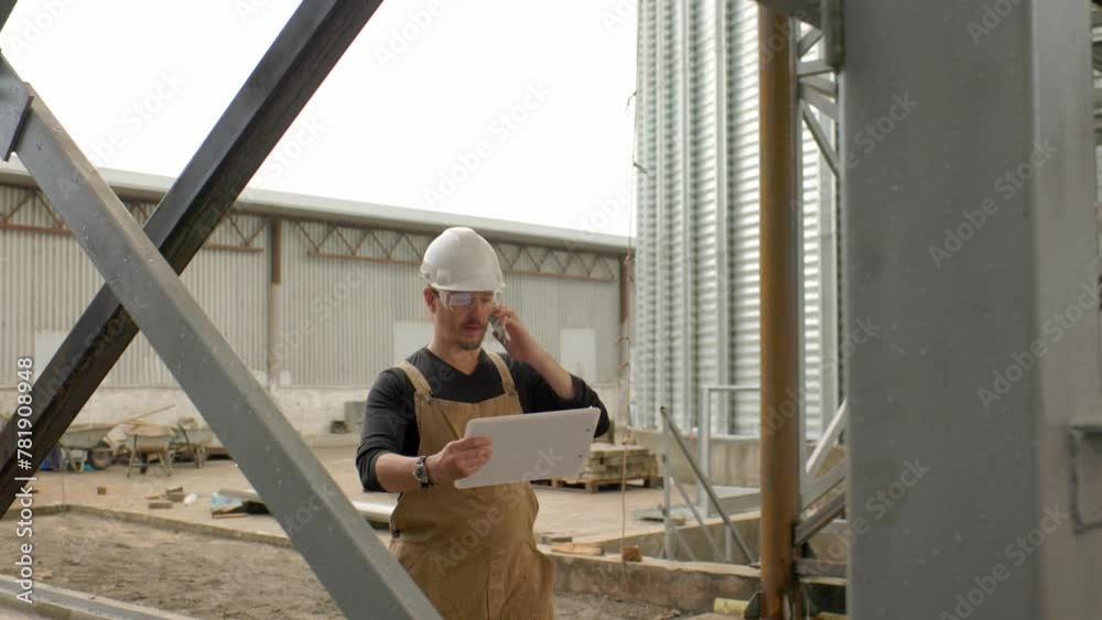 An engineer inspects the construction of grain storage silos. An engineer inspects the construction of grain storage silos.