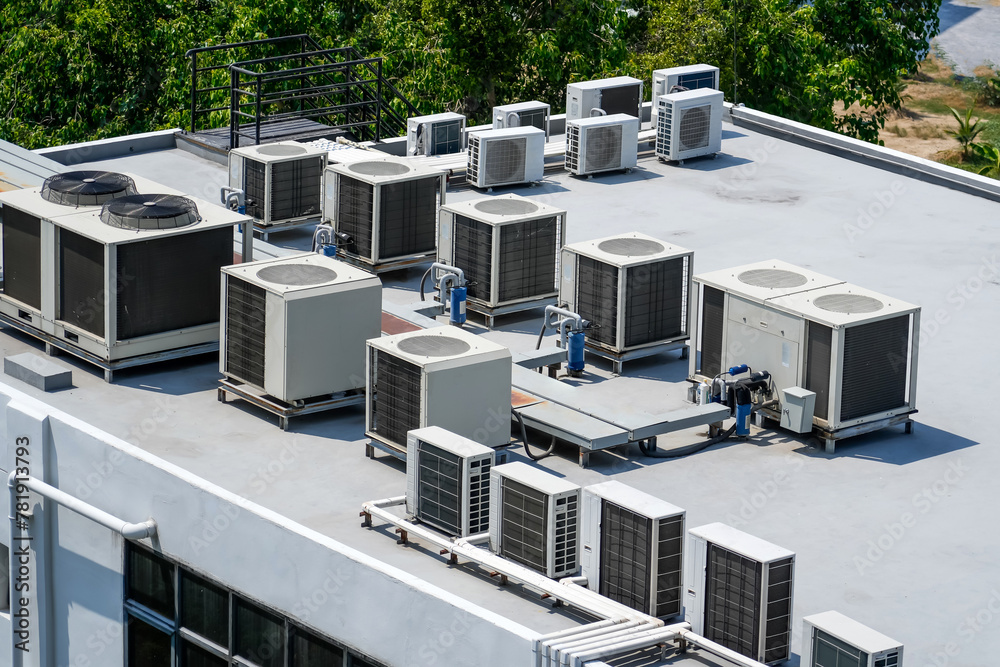 The external units of the commercial air conditioning and ventilation systems are installed on the roof of an industrial building. - obrazy, fototapety, plakaty 