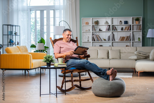 Photography Indian asian mid age man looking at photo frame while sitting on rocking chair i