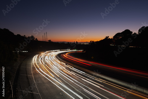 View of light streaks created by traffic coming from San Francisco and Oakland at sunset, as seen from an overpass over Highway 24.