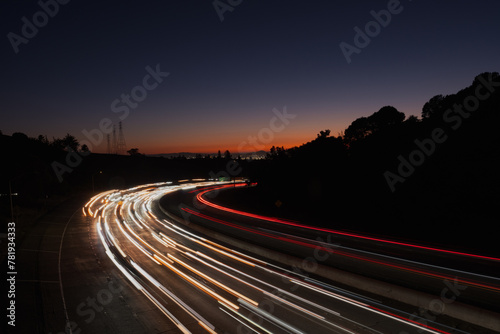 View of light streaks created by traffic coming from San Francisco and Oakland at sunset, as seen from an overpass over Highway 24.