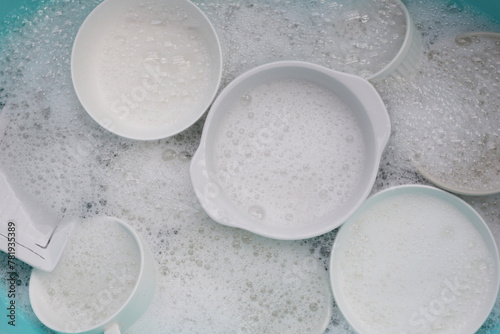 Plates and bowl soaking in foam of dishwashing liquid