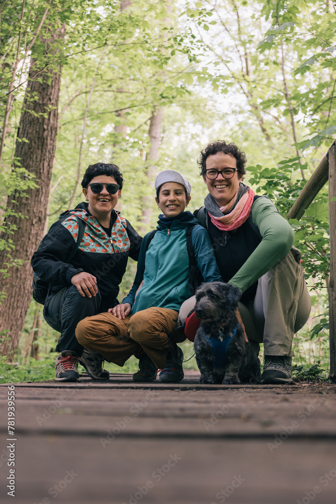 Fototapeta premium Family hiking in the woods with their little black dog