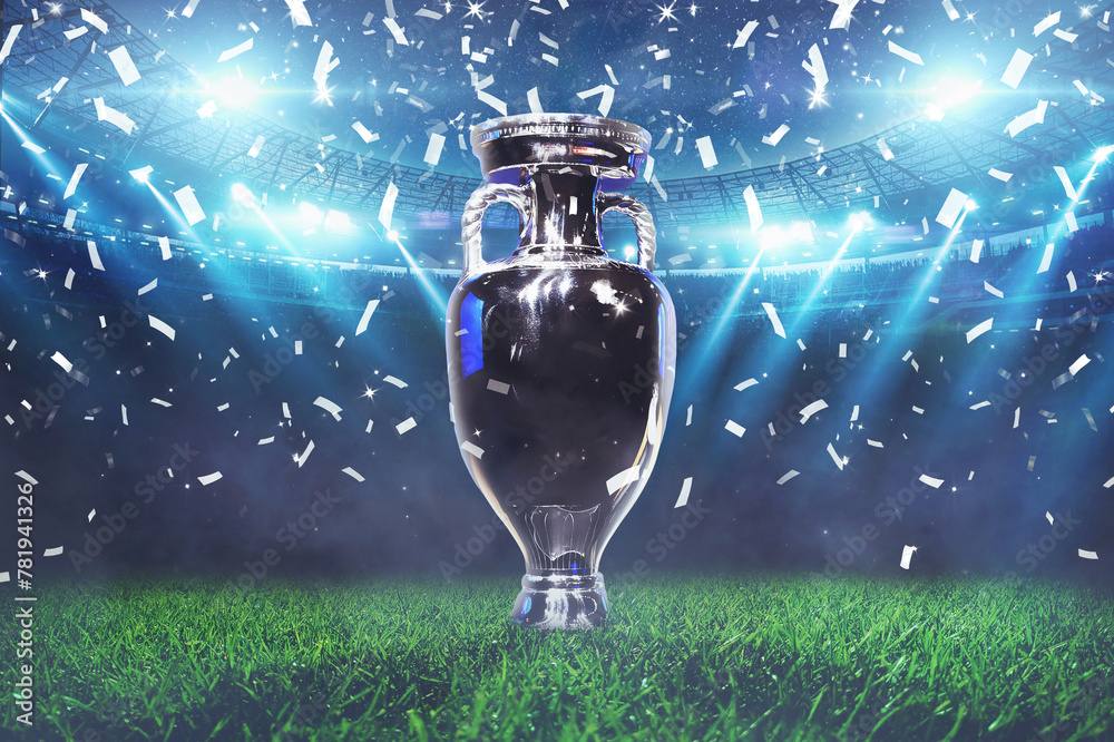 Naklejka premium The champion cup stands on a green field at a football stadium with the light of spotlights and confetti. Football cup final, creative idea. Euro 2024 celebration