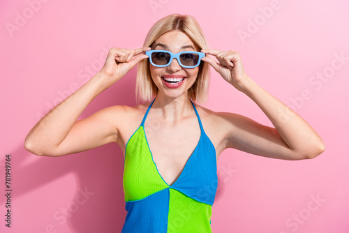 Portrait of satisfied woman with bob hair wear colorful top touch 3d glasses staring at visual effect isolated on pink color background