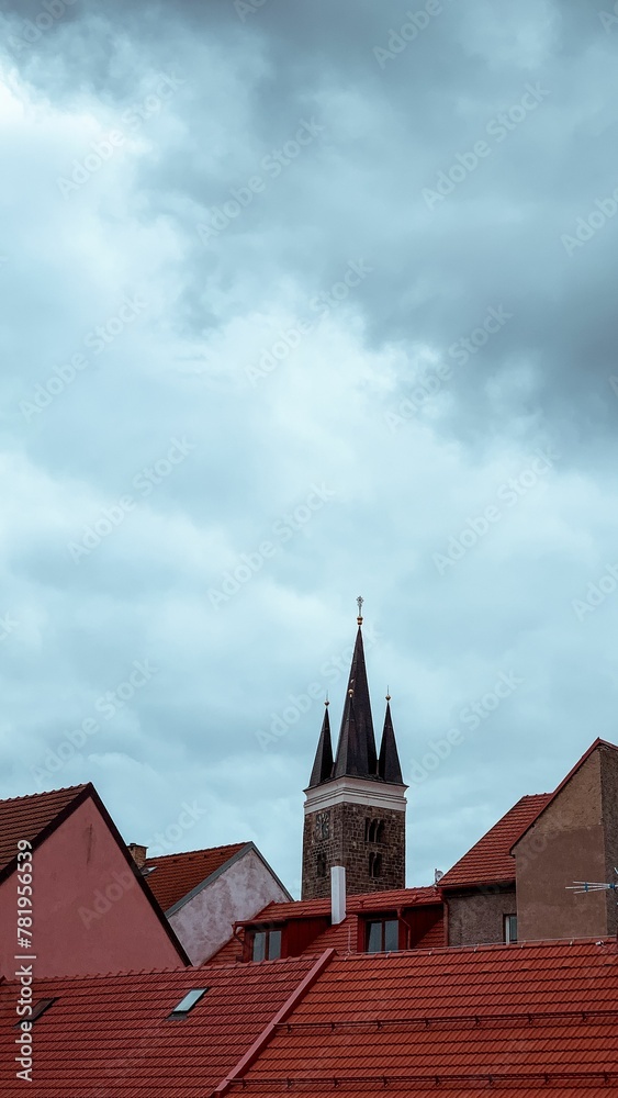 Obraz premium Beautiful view of an old tower and rooftops under the cloudy sky