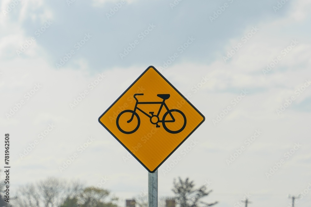 Closeup of a yellow bicycle sign outdoors with clouds in the background Closeup of a yellow bicycle sign outdoors with clouds in the background