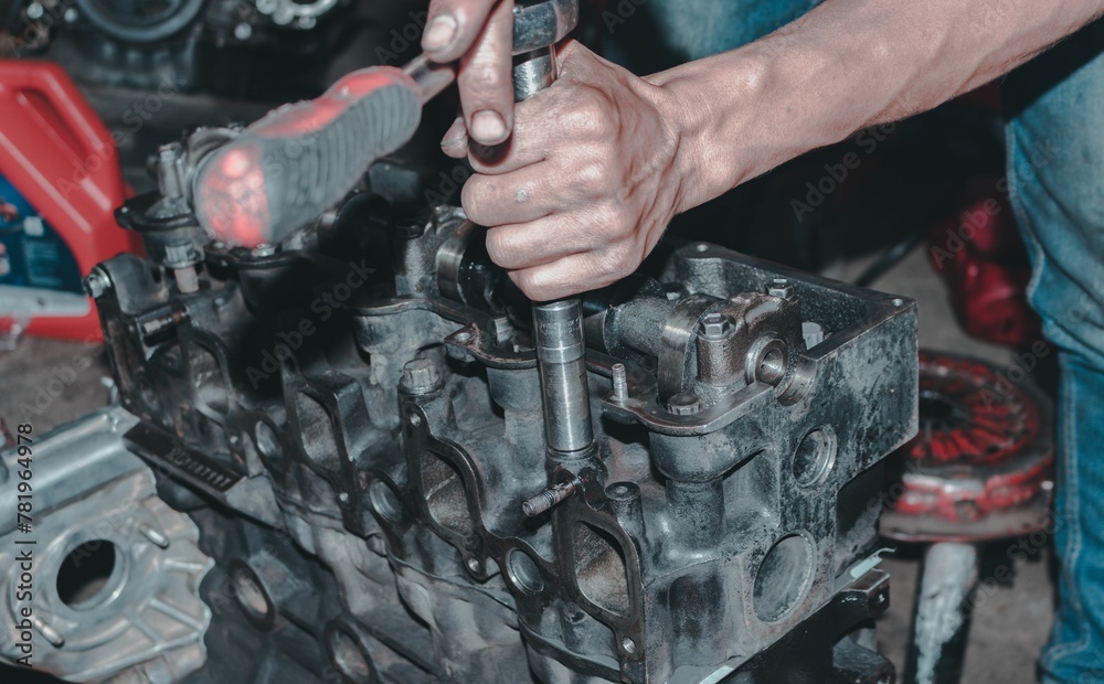 Fototapeta premium Auto mechanic repairing the engine of a car with different tools