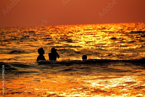 Silhouette of a group of people in the sea at sunset