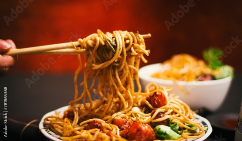 Closeup view of noodles with Manchurian and Schezwan sauce on a chopstick photo