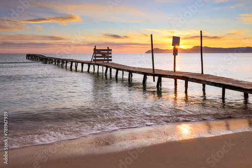 Beautiful sunrise on a beach with old wooden jetty in Platja de Muro, Majorca, Balearic Islands, Spain	 photo