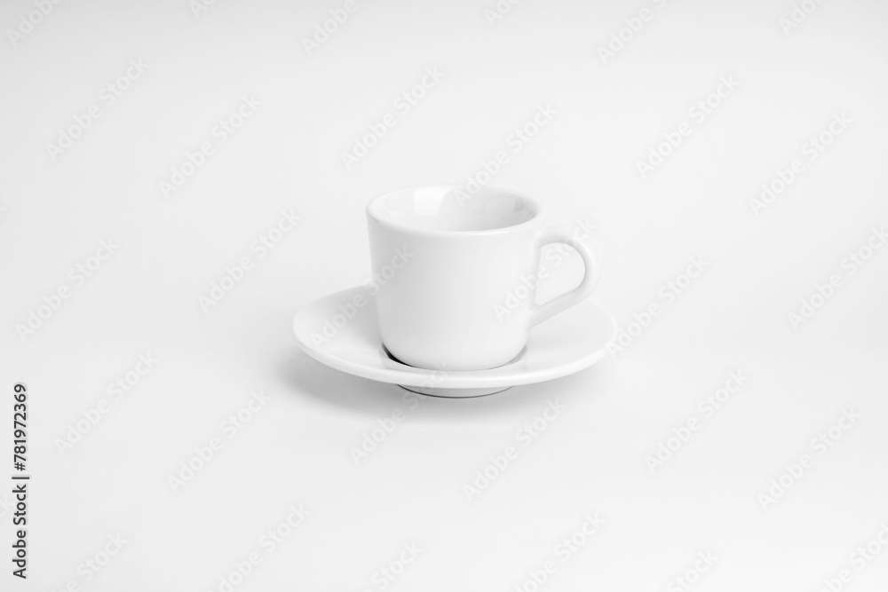 White cup of coffee with its plate on a white surface