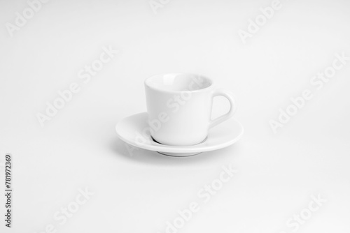 White cup of coffee with its plate on a white surface