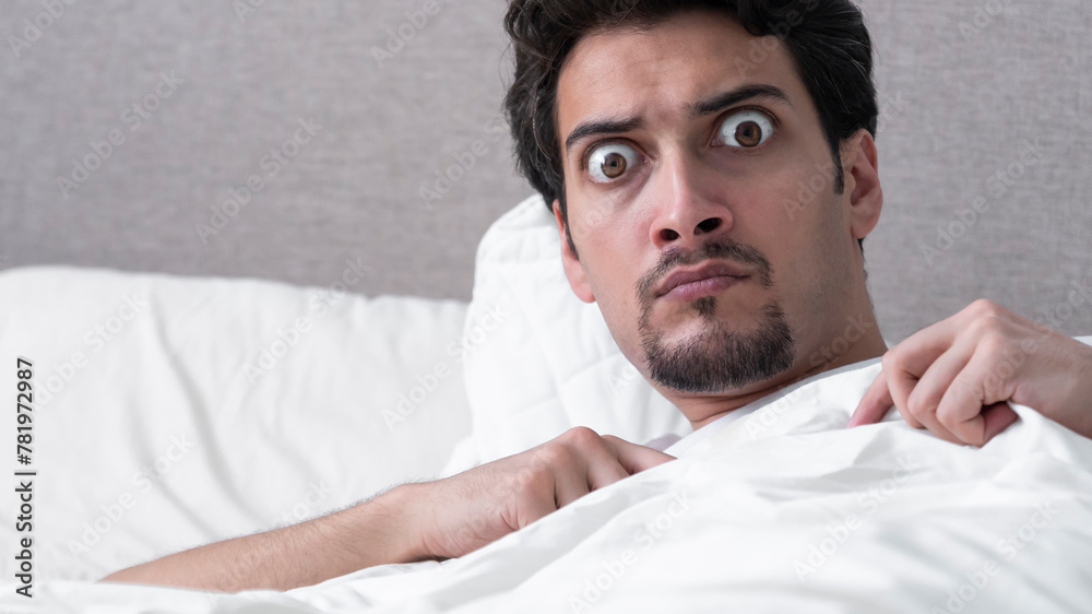© Vitaliy - A man frightened in a dream wakes up and looks at the camera with huge bulging eyes