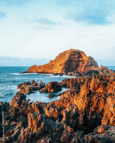 Vertical shot of the brown cliffs and blue sea. Porto Moniz, Portugal. photo