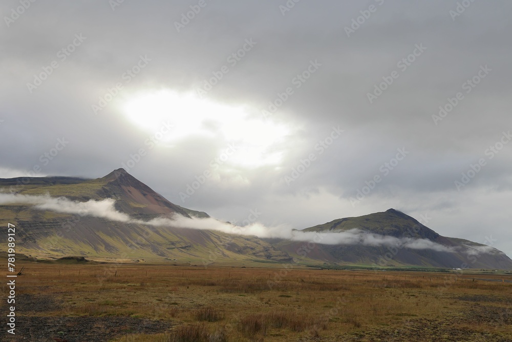 Scenic view of a field against a mountain range on a cloudy day in Iceland