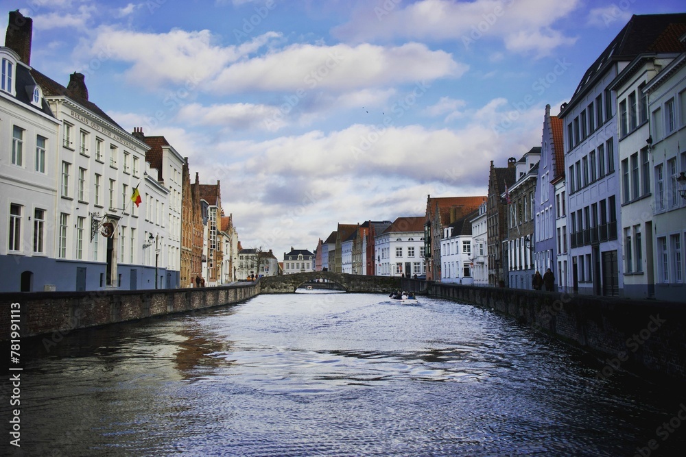 Naklejka premium Beautiful shot of a flowing canal through historic buildings in Bruges, Belgium
