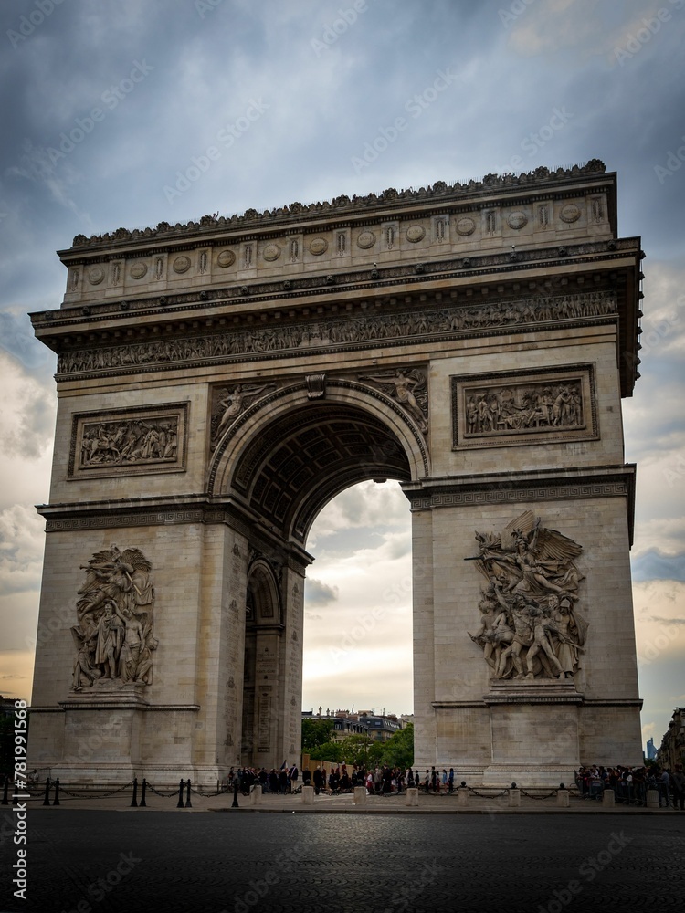 Exterior of Arc de Triomphe under dramatic cloudy sky in Paris, France
