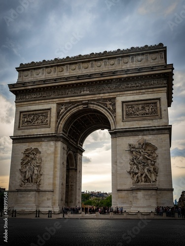Exterior of Arc de Triomphe under dramatic cloudy sky in Paris, France © Wirestock