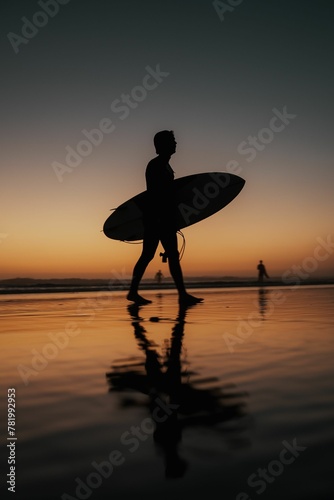 Vertical shot of a person with a surfing board walking on the beach at sunset perfect for wallpapers
