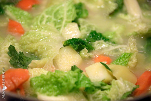 Stew dish, soup with healthy vegetables such as potatoes, savoy cabbage, carrots and herbs, close up.