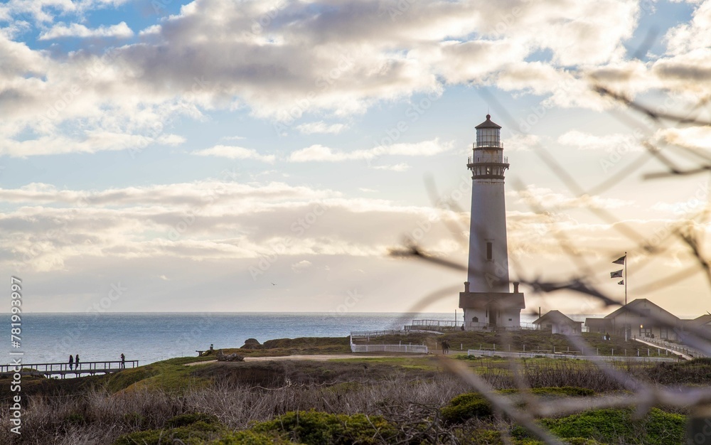 Fototapeta premium a view from the beach looking at a lighthouse, the sky and water