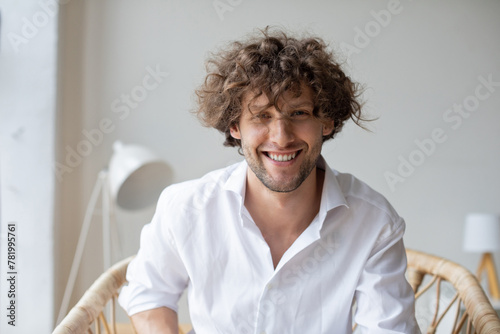 Close-up portrait of a handsome smiling emotional man in a cozy chair, friendly communication online.