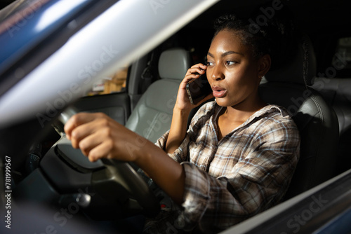 young woman driving a car and talking on smartphone or cellphone