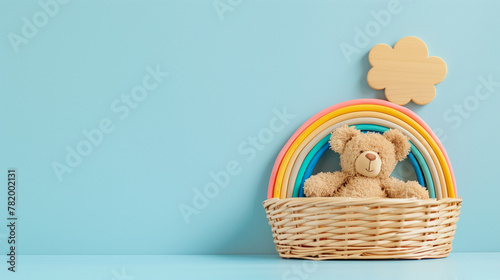 Photo of kids toys in wooden basket on blue background, teddy bear and rainbow color toy in front view, copy space concept for baby room decoration, minimal style 
