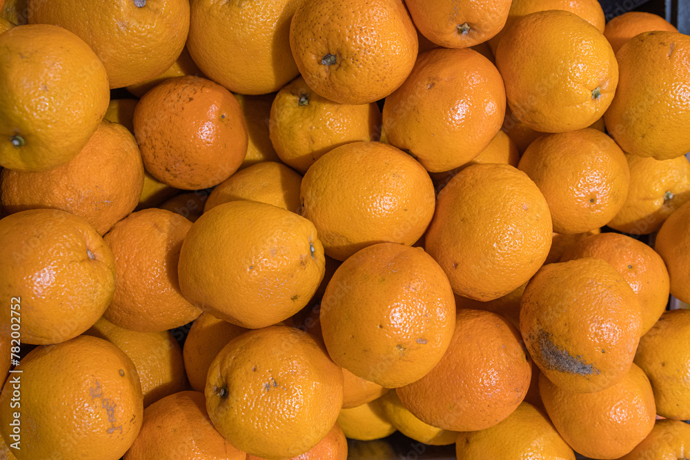 Orange fruits pile on the farmer market counter. Fresh mandarin oranges texture. Top view texture of dirty oranges, market sale. Food market stand. Minimalist, simple concept. Selective focus. Orange fruits pile on the farmer market counter. Fresh mandarin oranges texture. Top view texture of dirty oranges, market sale. Food market stand. Minimalist, simple concept. Selective focus.