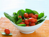 Bowl with tomatoes and spinach on an orange tablecloth..