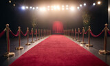 The image features a red carpet with a gold barrier in the foreground and a stage at the end of the carpet. 
