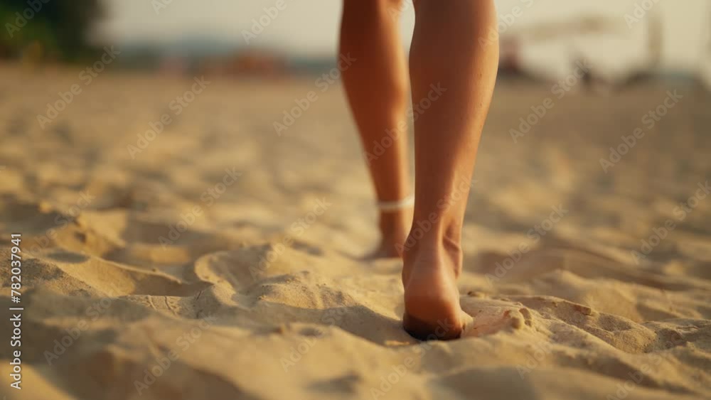 Woman feet barefoot on beach close up. Female tourist walking on the beach by sea ocean, enjoying the sunrise. Close up of legs footstep in sea water. Travel and tourism, warm vacation concept.