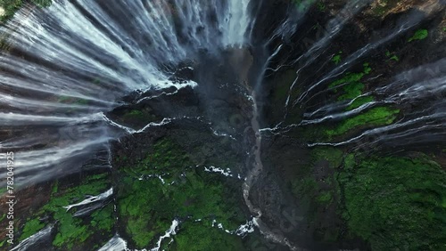 Aerial top view drone rise up and spin from bottom of Tumpak Sewu waterfall