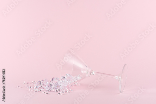 Spilled martini glass full of diamonds on a pink background. Creative minimal party concept.