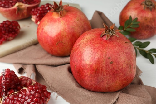 Fresh pomegranates and seeds on white table, closeup