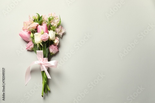 Happy Mother's Day. Bouquet of beautiful flowers tied with pink ribbon on light grey background, top view. Space for text © New Africa