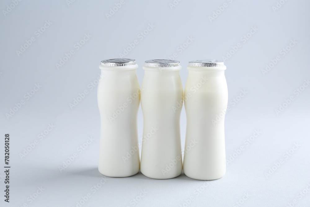 Tasty yogurt in bottles on light grey background Tasty yogurt in bottles on light grey background