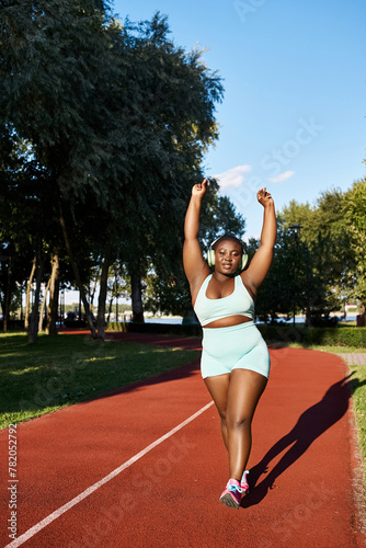 An African American woman in sportswear runs on a track, showcasing her athleticism and body positivity. © LIGHTFIELD STUDIOS