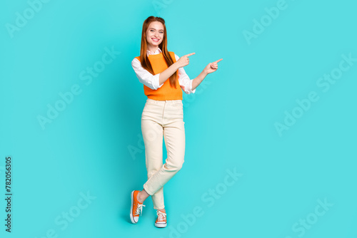 Full length photo of charming cute girl wear trendy clothes demonstrates empty space isolated on aquamarine color background