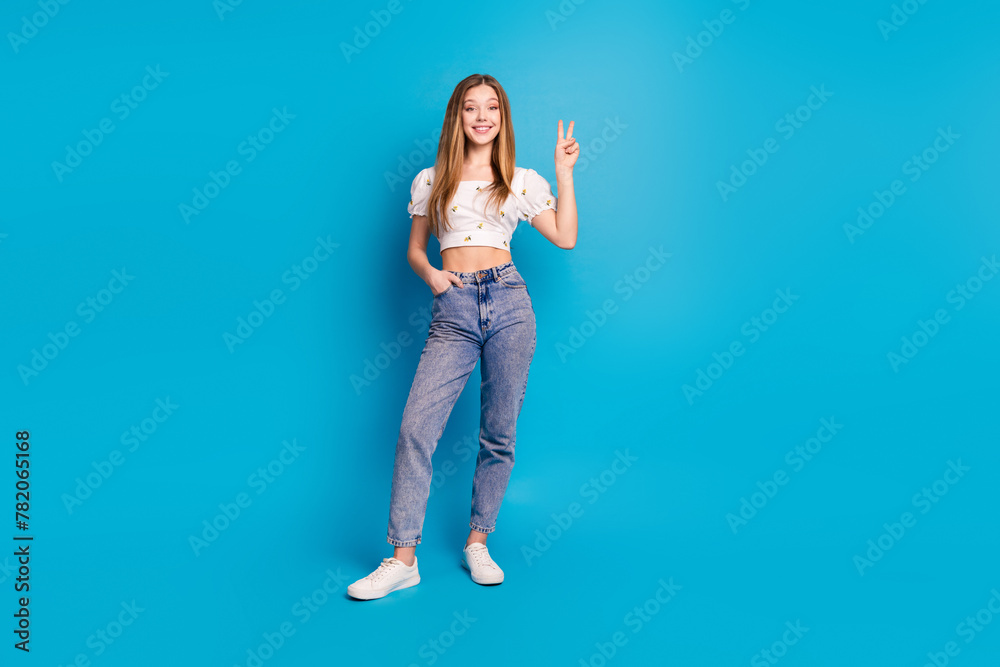 Photo of positive girl stand make v sign isolated blue color background - obrazy, fototapety, plakaty 