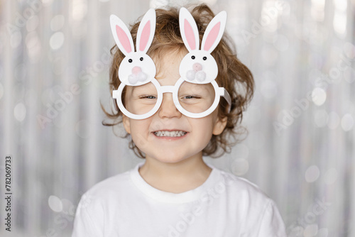 Cute little blond boy wearing glasses in the shape of bunny ears for Easter