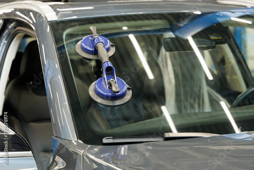 Automobile special workers replacing windscreen or windshield of a car in auto service station garage photo