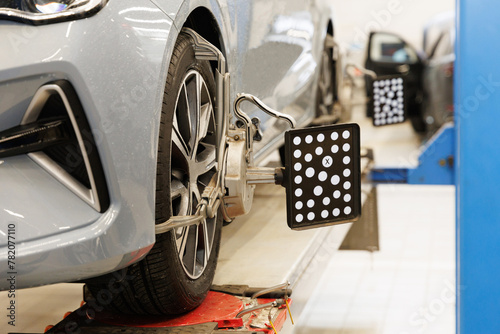 CLose-up car wheel indoors service maintenance repair center against laser sensor equipment diagnostics and 3d wheel alignment